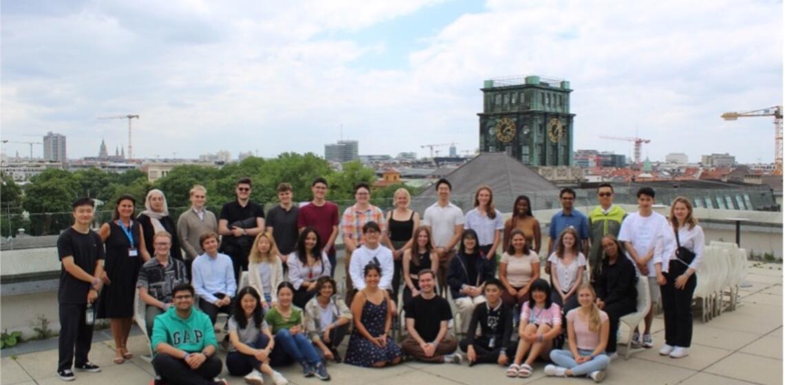 A group of TUM PREP students sit on a rooftop with the Munich skyline in the background